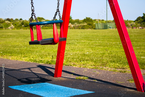 Empty toddler swing with the frame in the playground on a sunny day