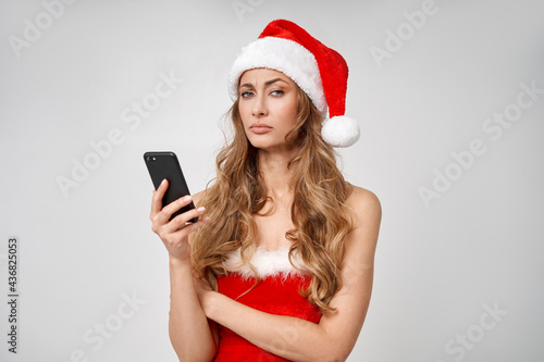 Woman christmas Santa Hat white studio background with smartphone in hand