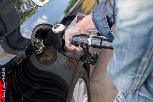 Woman's hand with gloves holding hose from gas pump