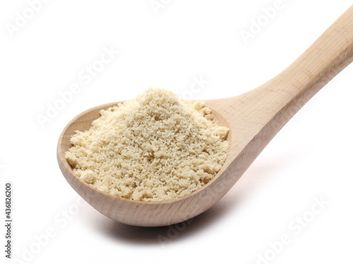 Organic sesame protein powder in wooden spoon, supplement isolated on white background