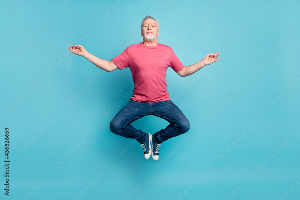 Full length body size photo of bearded man smiling jumping high practising yoga isolated pastel blue color background