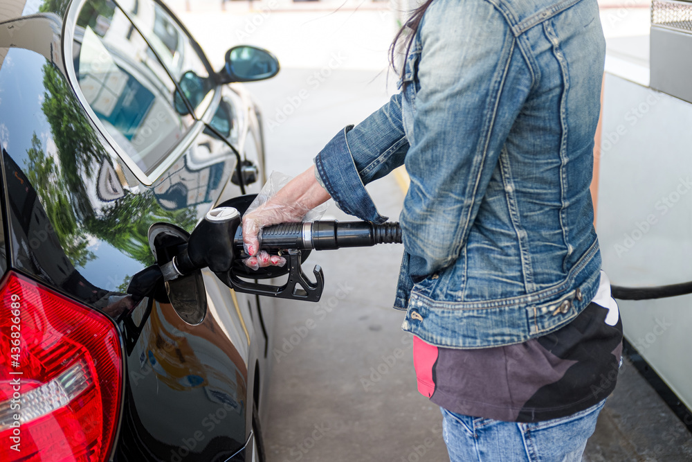 Woman's hand with gloves holding hose from gas pump Woman's hand with gloves holding hose from gas pump