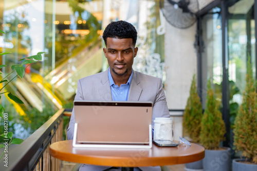 African businessman at coffee shop using laptop computer