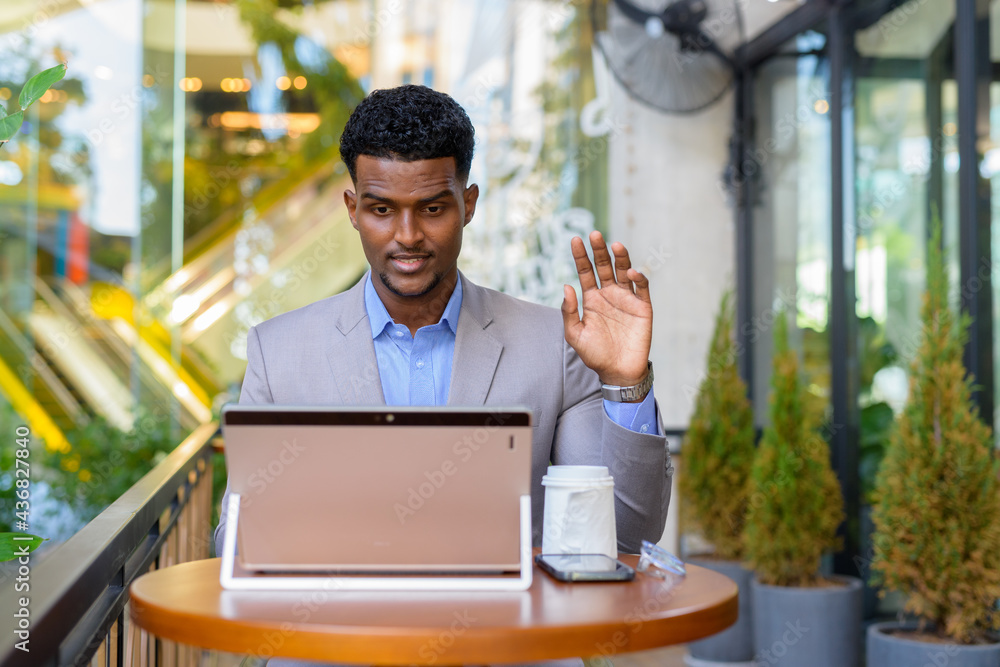 African businessman at coffee shop using laptop computer to make video call African businessman at coffee shop using laptop computer to make video call