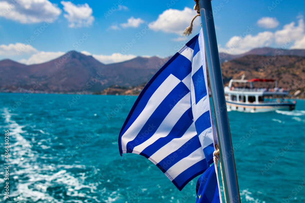 Greek waving flag on a ship off the Greek coast