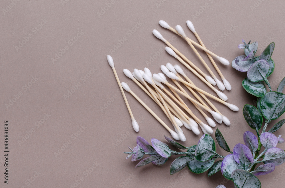 Top view of pile of wooden ear sticks,green leaves of eucalyptus on the beige surface.Empty space Top view of pile of wooden ear sticks,green leaves of eucalyptus on the beige surface.Empty space