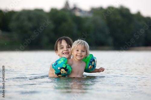 Children, playing in a lake on sunset, swimming and running, splashing water, summertime