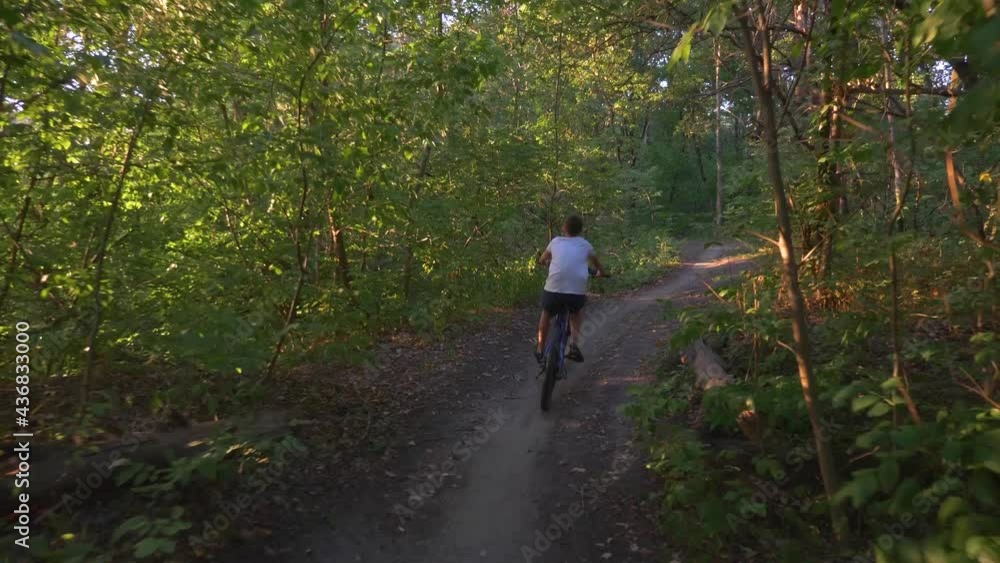 A happy child rides a bicycle in a park in the open air. Cycling on a path in the woods. Active rest of the child. Healthy lifestyle, children's sports. A happy child rides a bicycle in a park in the open air. Cycling on a path in the woods. Active rest of the child. Healthy lifestyle, children's sports.
