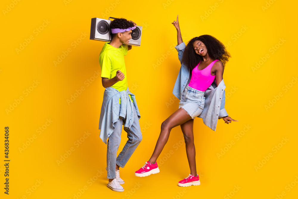 Obraz premium Photo of charming sweet young people wear jeans clothes dancing holding boombox isolated yellow color background