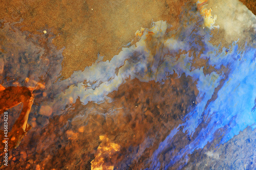 puddle gasoline background, wet oil multicolored rainbow pollution spill © kichigin19