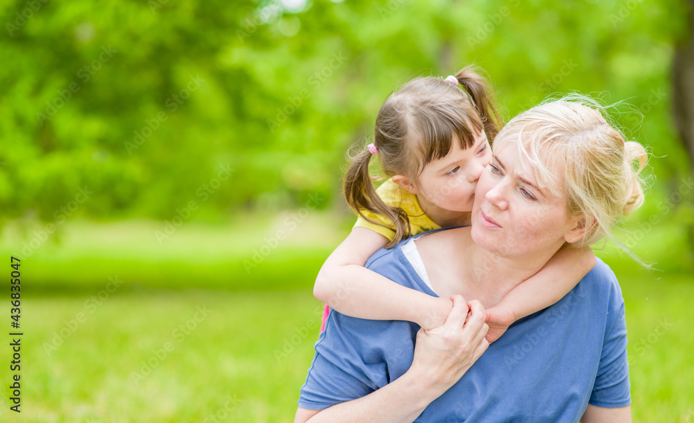 Little girl with special needs hugs and kisses her mother at summer park. Empty space for text Little girl with special needs hugs and kisses her mother at summer park. Empty space for text