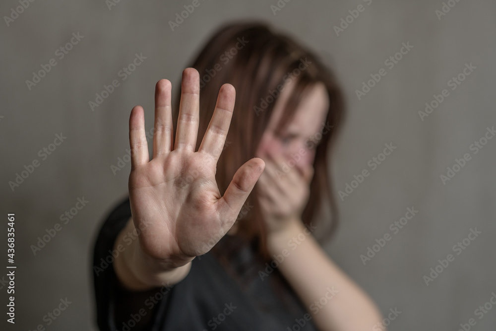 Crying teenage girl showing a stop sign with her hand. Focused on the hand Crying teenage girl showing a stop sign with her hand. Focused on the hand
