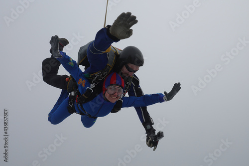 Skydiving. Tandem jump. A young woman and her instructor are in the sky. 