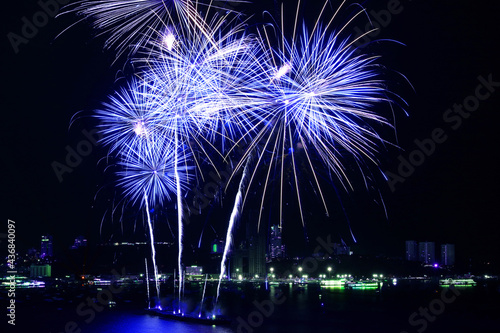Stunning blue and white fireworks exploding into the night sky over the bay	