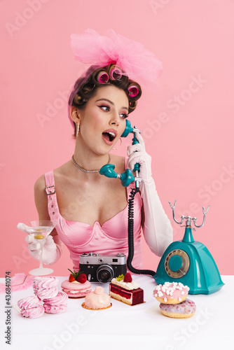 Valokuva Young woman barbie in pink dress calling on landline