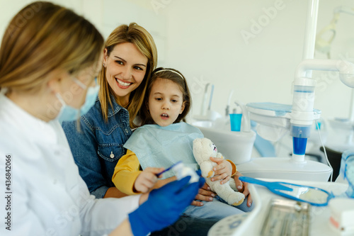 Girl is teaching how to brush teeth properly.Dentist is showing to girl patient how to brush teeth