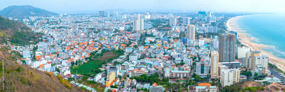 Aerial view on Vung Tau, Vietnam which is the popular beach city. There are crowded small building close to the sea and mountain.