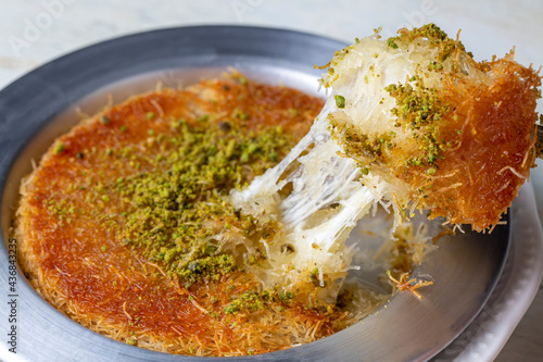 Delicious traditional Turkish kunefe with pistachio on it. Served hot and with syrup photo