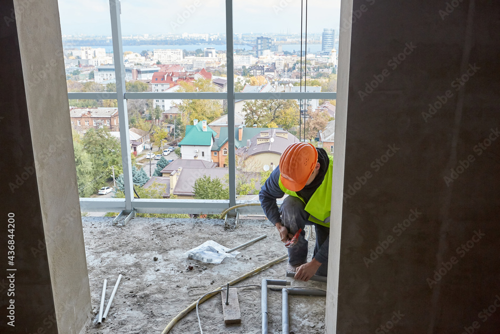 custom made wallpaper toronto digitalWorker in protective clothing and safety helmet installing plastic pipes using modern tools in flat of building under construction