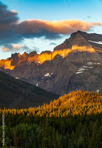 dramatic summer sunrise in Swift Current Lake in Many Glacier area in Glacier National park with the Grinnell Mt being illuminated by the sunrise .
