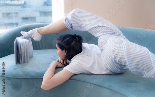 Bild auf Leinwand very flexible Beautiful young woman reading a book on the sofa