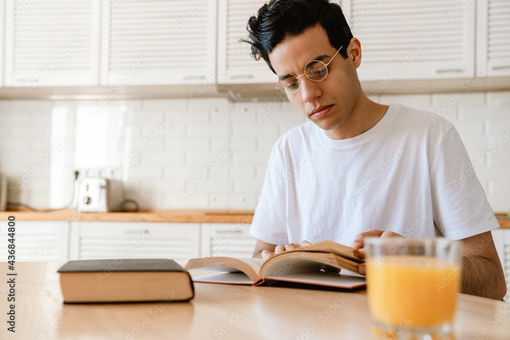 Young hispanic man reading a book while having breakfast Young hispanic man reading a book while having breakfast