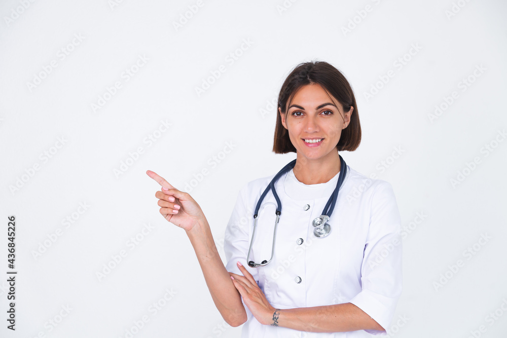 Female doctor in lab coat on white background isolated, confident smile point finger left