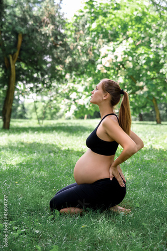 Pregnant woman sits in yoga posies and meditates. © jutaphoto