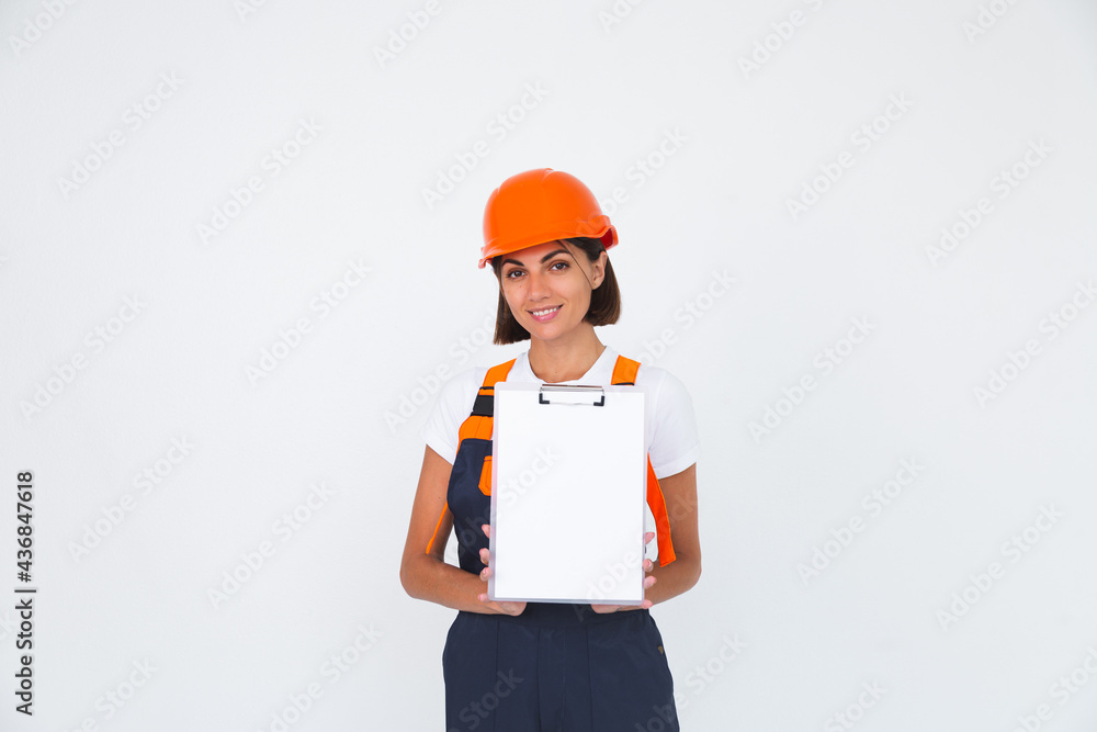 Pretty woman engineer in building protective helmet on white background smile hold white paper blank with empty space Pretty woman engineer in building protective helmet on white background smile hold white paper blank with empty space