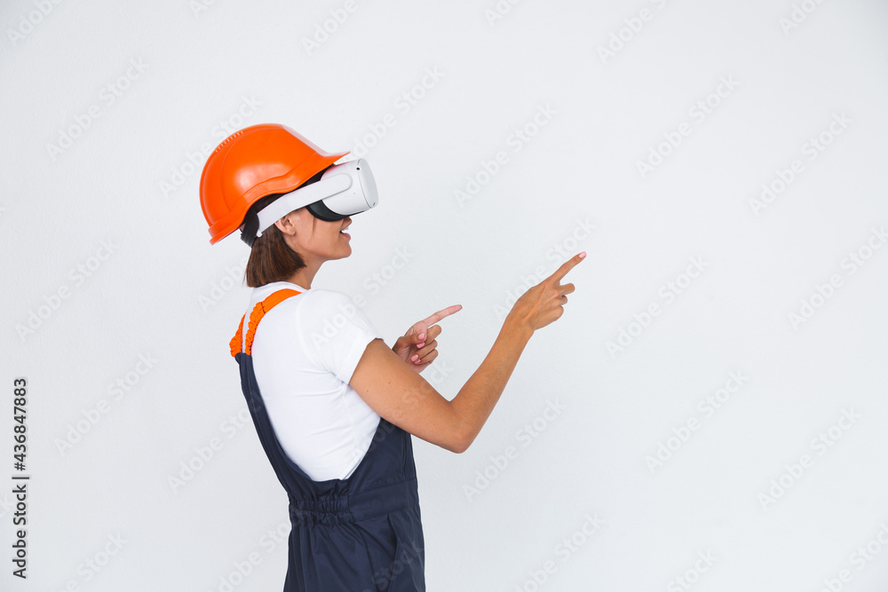 Pretty woman engineer in building protective helmet on white background in virtual reality glasses Pretty woman engineer in building protective helmet on white background in virtual reality glasses