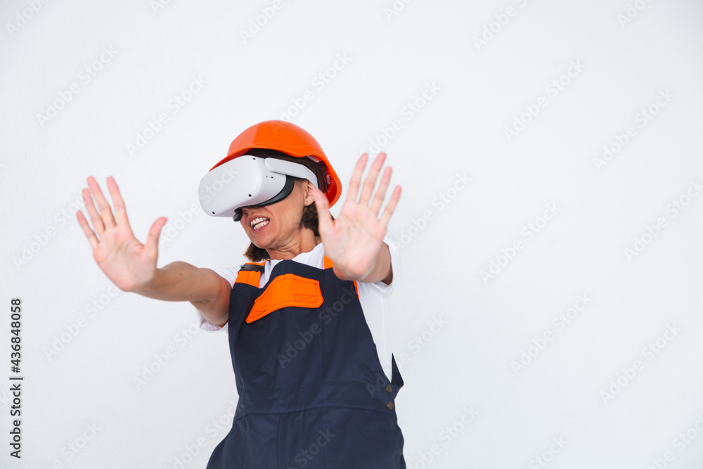 Pretty woman engineer in building protective helmet on white background in virtual reality glasses Pretty woman engineer in building protective helmet on white background in virtual reality glasses