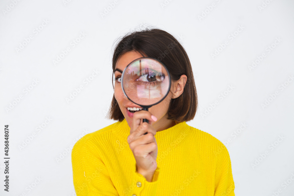 Pretty woman in yellow sweater on white background held magnifier happy positive playful Pretty woman in yellow sweater on white background held magnifier happy positive playful