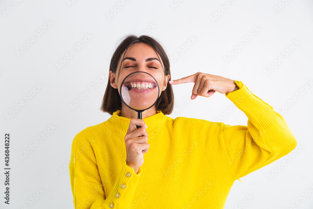 Pretty woman in yellow sweater on white background held magnifier happy positive showing white snow teeth smile Pretty woman in yellow sweater on white background held magnifier happy positive showing white snow teeth smile