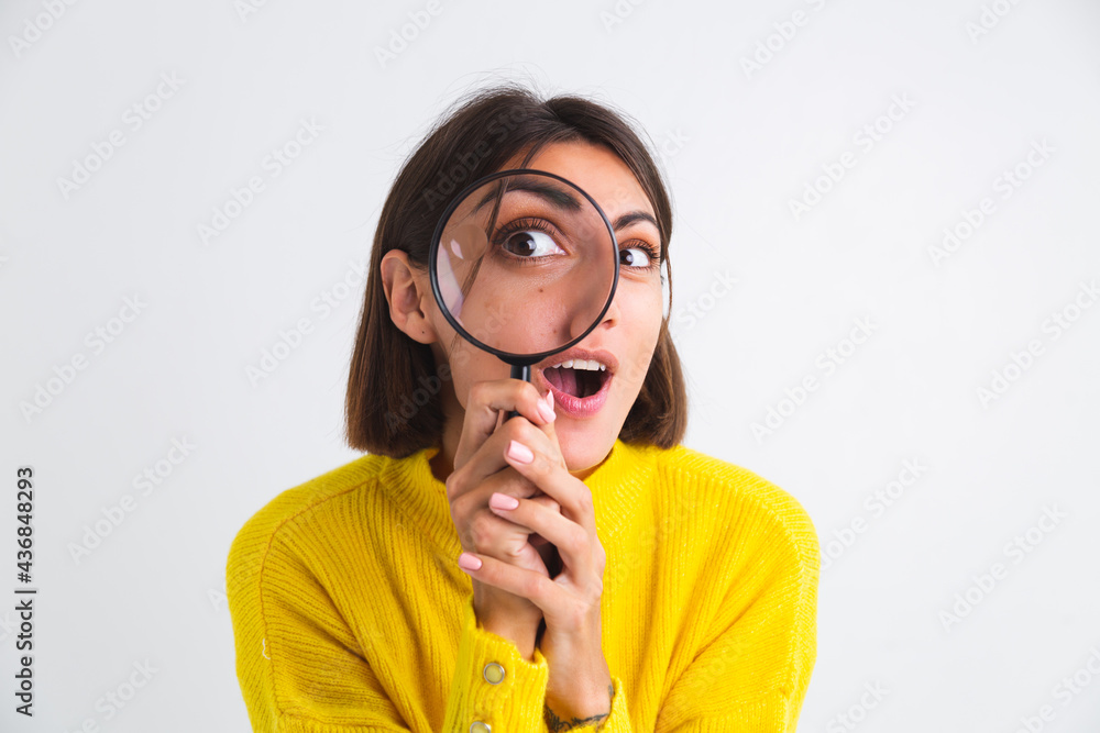 Pretty woman in yellow sweater on white background held magnifier happy positive playful Pretty woman in yellow sweater on white background held magnifier happy positive playful