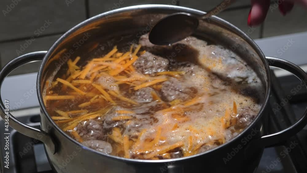 Women's hands stirring homemade bouillon with meatballs. Preparation of meatball soup. Close-up. Selective focus Women's hands stirring homemade bouillon with meatballs. Preparation of meatball soup. Close-up. Selective focus