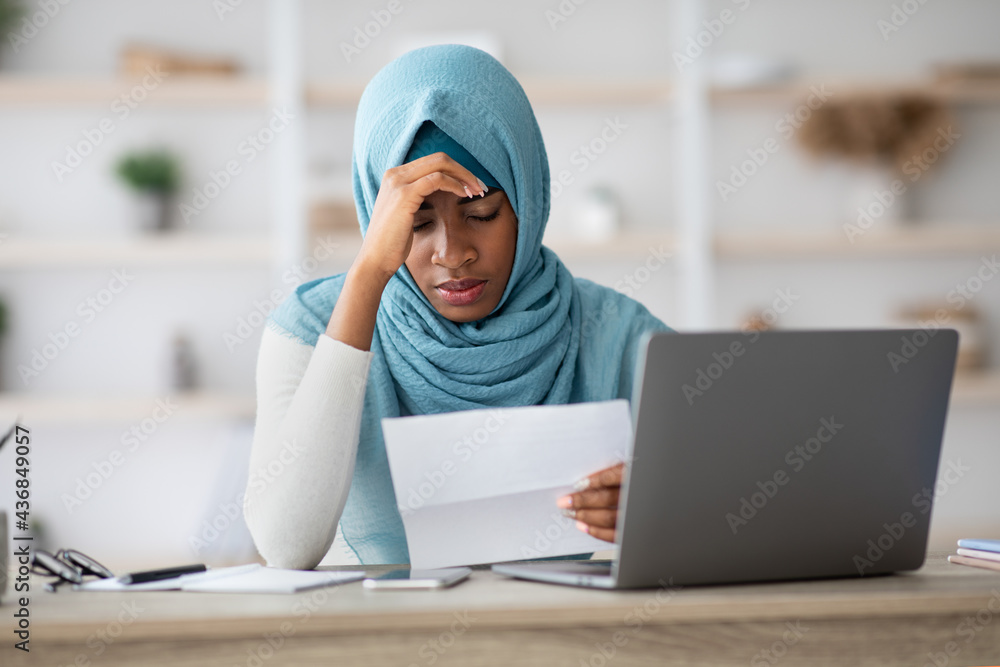 Stressed Black Muslim Woman Working With Papers And Laptop In Office Stressed Black Muslim Woman Working With Papers And Laptop In Office