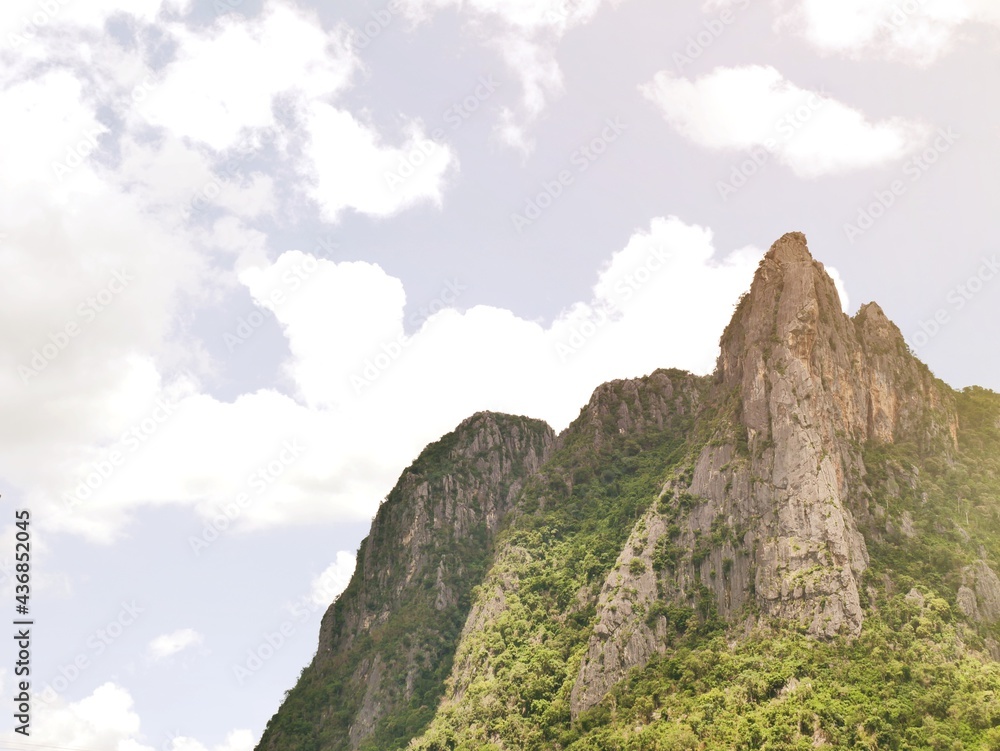 The steep mountain cliff overlooking the sky and white clouds.