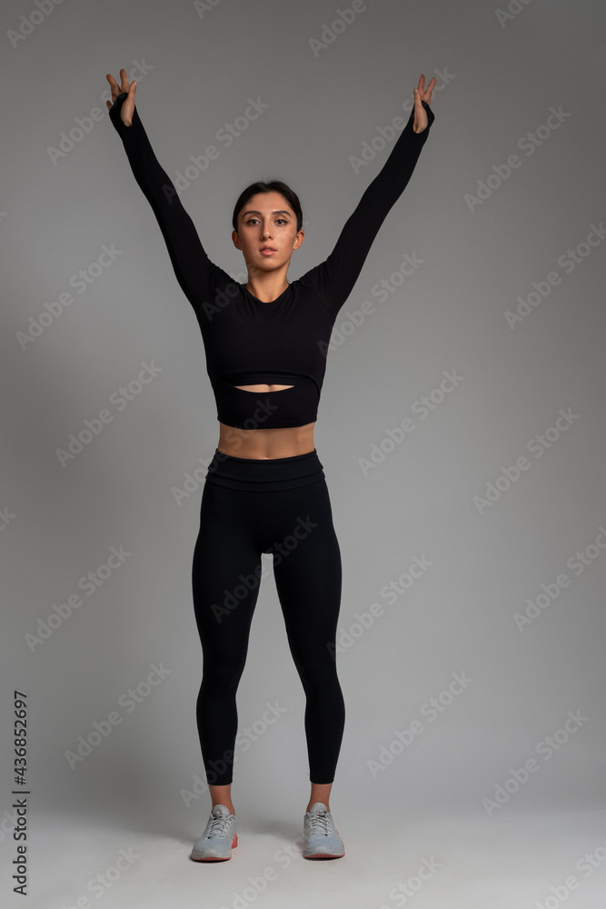 Woman doing stretching exercise on grey background Woman doing stretching exercise on grey background
