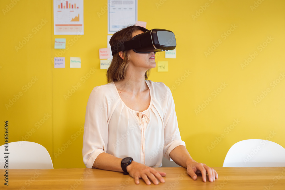 Caucasian woman sitting at desk using vr headset at work Caucasian woman sitting at desk using vr headset at work