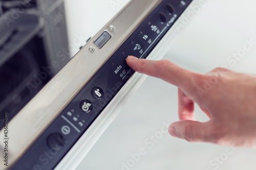 Foto Man choosing eco mode program on the control panel of the dishwasher