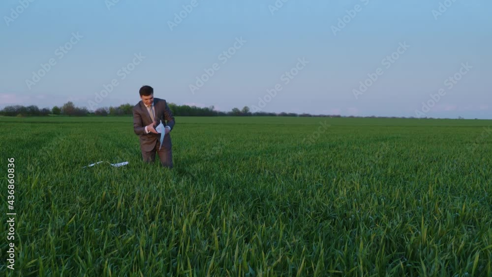 businessman collects reports in a green field, freelance and business concept, green grass and blue sky as background businessman collects reports in a green field, freelance and business concept, green grass and blue sky as background