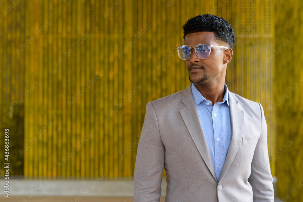 Portrait of stylish young African businessman outdoors wearing eyeglasses and smiling Portrait of stylish young African businessman outdoors wearing eyeglasses and smiling