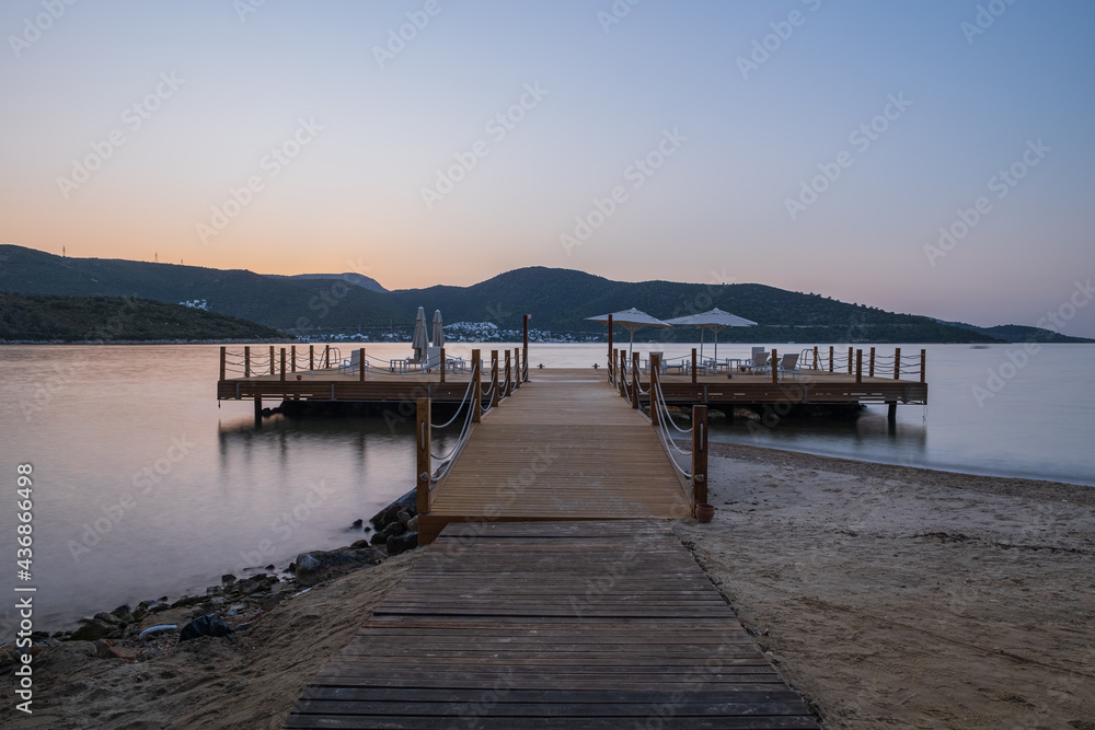 Fototapeta premium sunset over bay in Aegean sea. Torba, Bodrum, Turkey. October 2020. Long exposure picture with pier, jetty
