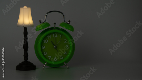 Bed time. Green clock showing 11 PM and floor lamp captured under low light.