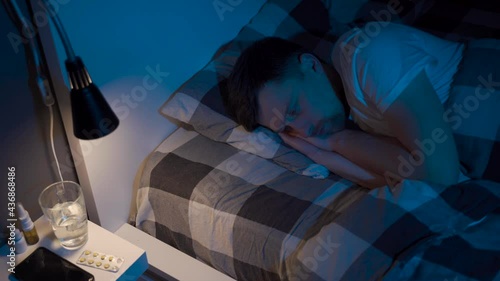 Depressed man lying in bed cannot sleep from insomnia. Young male trying to sleep. Restless worried guy wakes up at night lying on bed, sleepless, wide-eyed, suffering from insomnia, sleep disorder