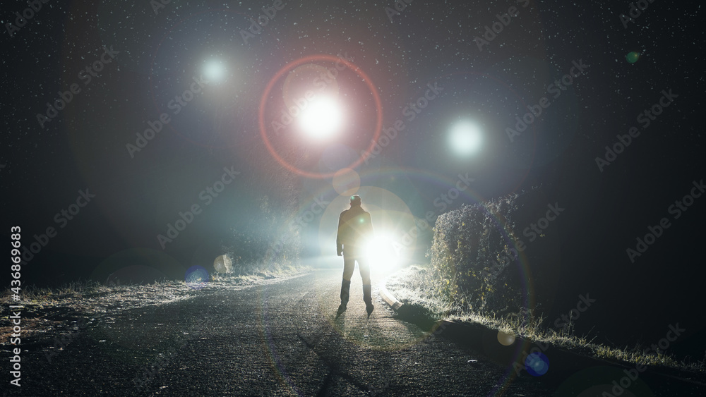 Naklejka premium UFO concept. Glowing orbs, floating above a misty road at night. With a silhouetted figure looking at the lights.