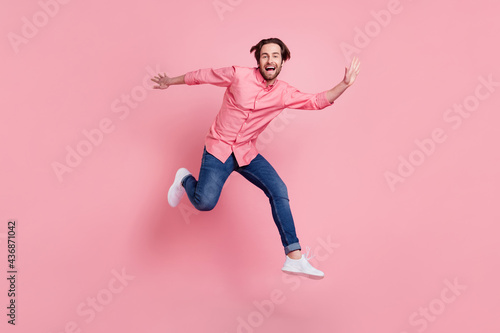 Full length body size view of attractive cheerful guy jumping having fun isolated over pink pastel color background