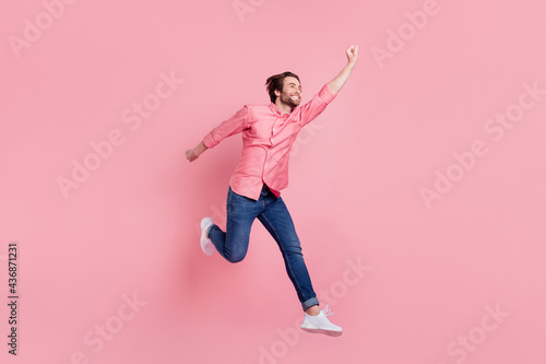 Full length body size view of attractive carefree cheerful guy jumping having fun success isolated over pink pastel color background