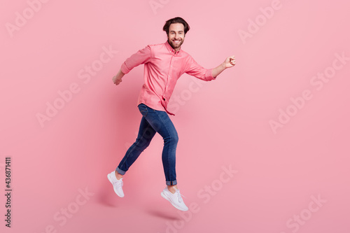 Full length photo of charming young happy man jump up run sale good mood isolated on pink color background
