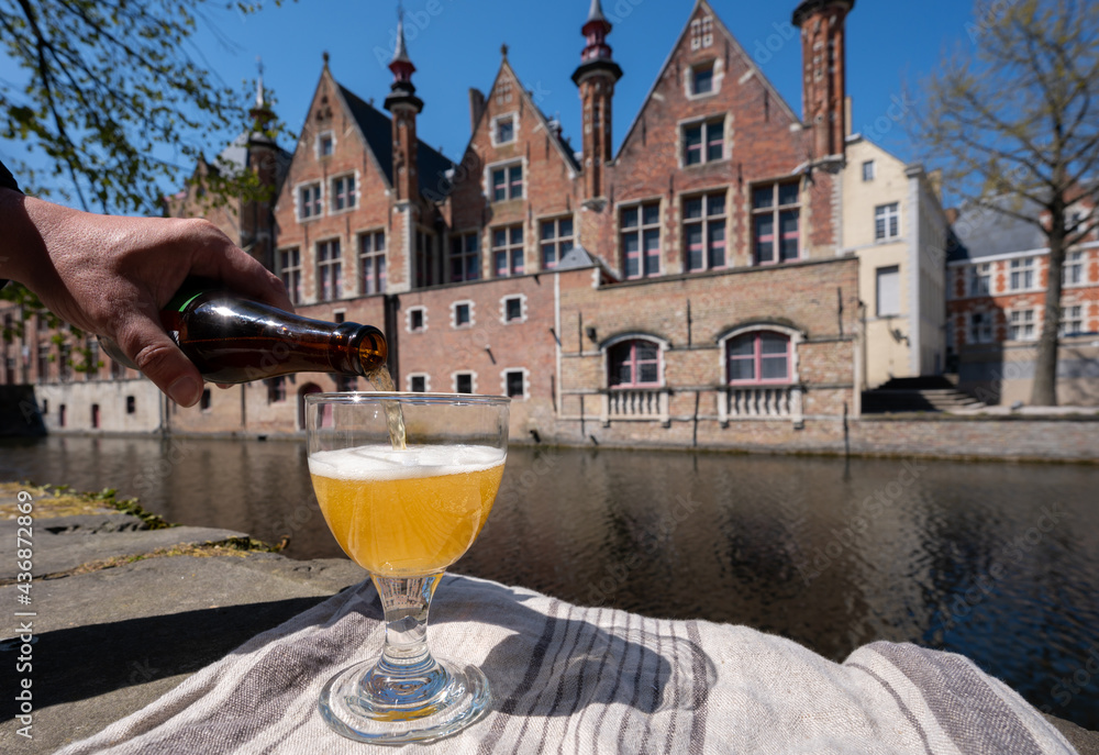 Naklejka premium Tasting of Belgian beer on open cafe or bistro terrace with view on medieval houses and canals in Bruges, Belgium